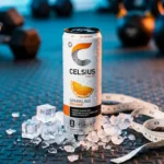 A cold Celsius energy drink can on a gym surface next to a measuring tape
