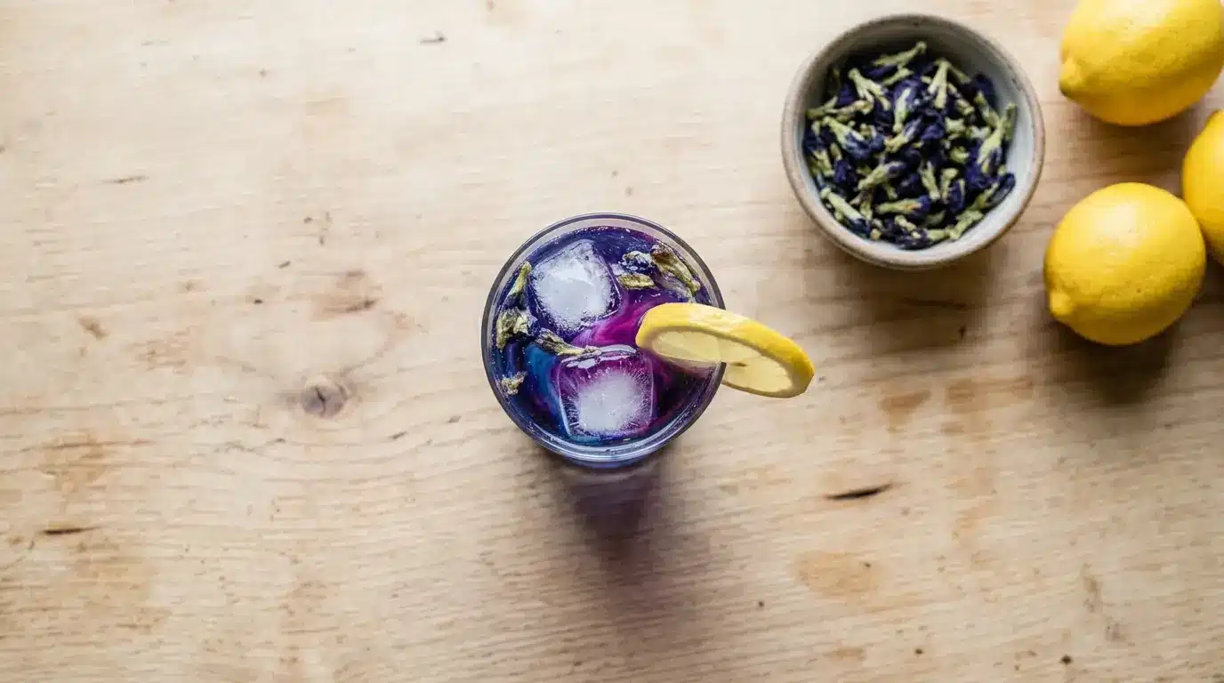 Glass of color-changing Brazilian Mounjaro tonic made with butterfly pea flower, lemon, and ice, garnished with a lemon wheel